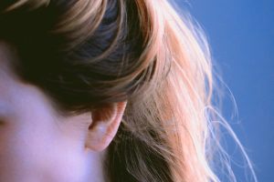 a close up of a woman's head with her hair in a pony tail